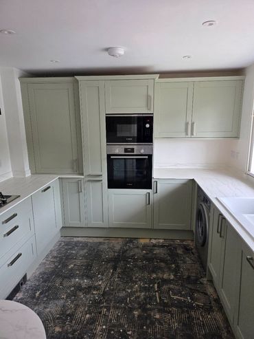 Modern kitchen with sage green cabinets and black textured floor.