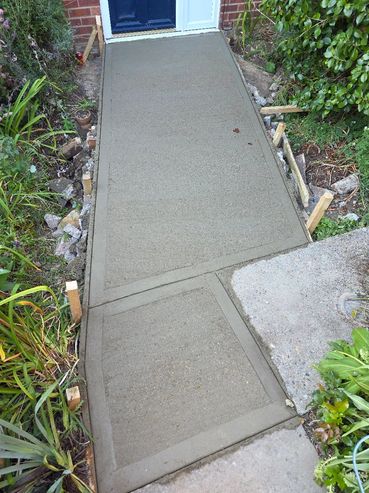 Newly poured concrete walkway leading to a blue door.
