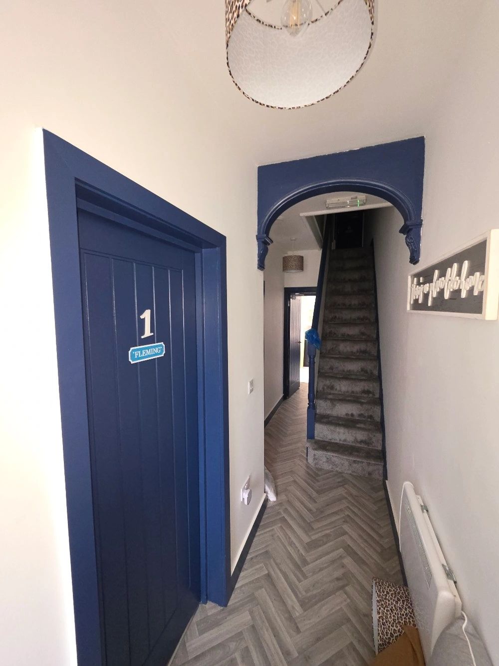 Modern hallway with blue door and carpeted stairs.