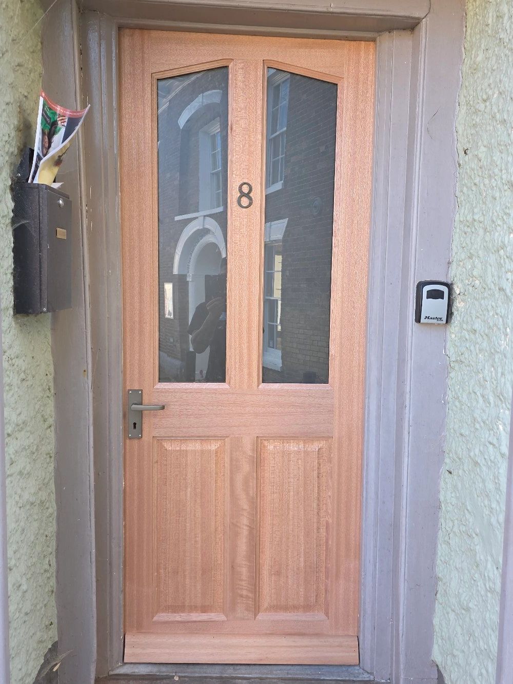 Wooden front door with glass panels and the number 8 on it.