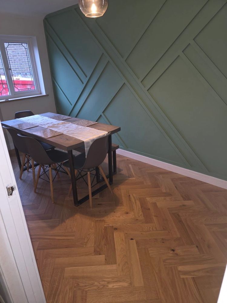 Modern dining area with wooden floor and green accent wall.