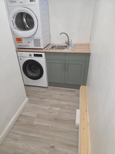 Compact laundry area with washer, dryer, sink, and modern cabinetry.