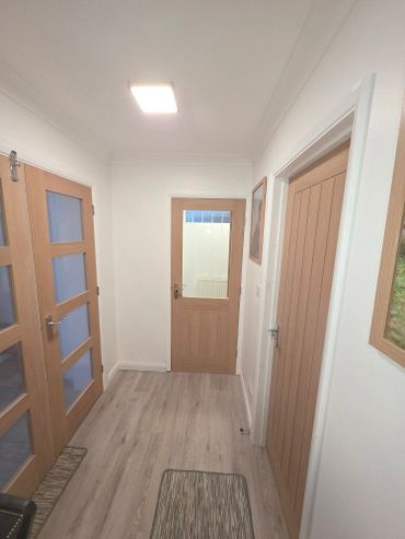 A bright hallway with wooden doors and light-colored flooring.