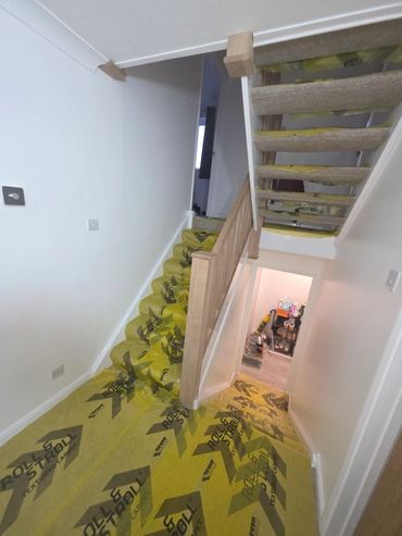 Staircase under renovation with protective yellow covering on steps and floor.