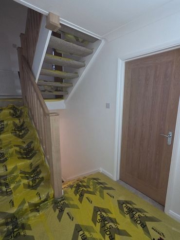 Indoor staircase with carpeted steps and protective yellow floor covering.