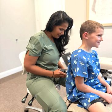 Dr. Ayesha is using a thermal scope on a boy's back to detect heat differences. 