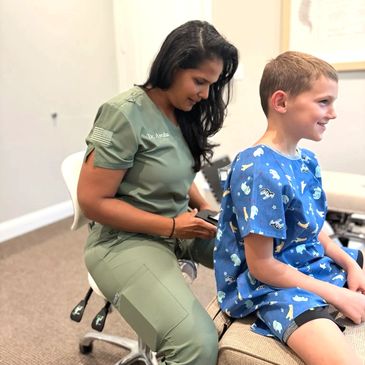 Dr. Ayesha is using a thermal scope on a boy's back to detect heat differences. 