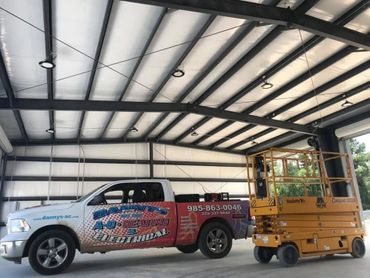 A branded truck and yellow scissor lift inside a large industrial building.