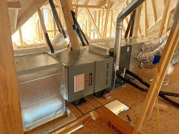 HVAC system installed in unfinished attic space with wooden framing.