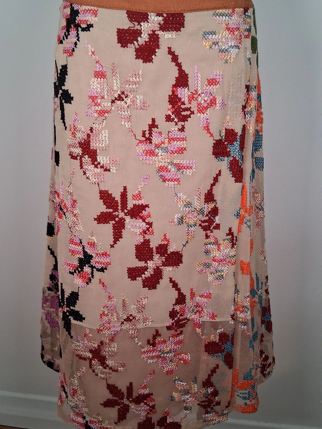 Beige skirt with colorful floral embroidery.