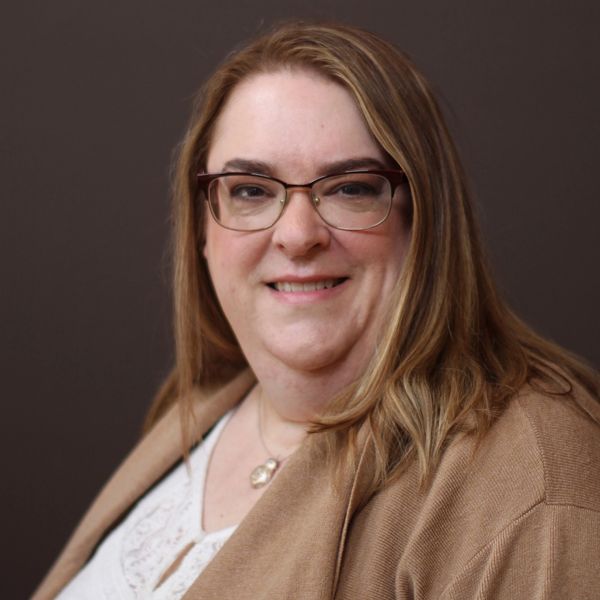 Smiling woman with glasses and long hair.