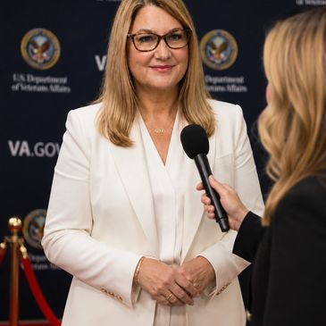 Woman in white suit being interviewed.