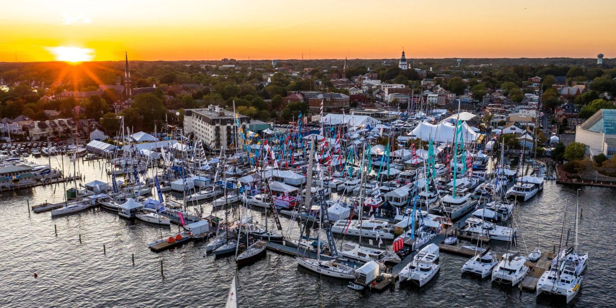 Sunset over a marina filled with sailboats and a city backdrop.