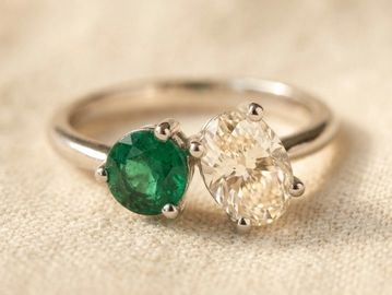 Elegant ring with emerald and diamond stones on silver band.