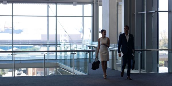 Two professionals walking and talking in a modern office building.