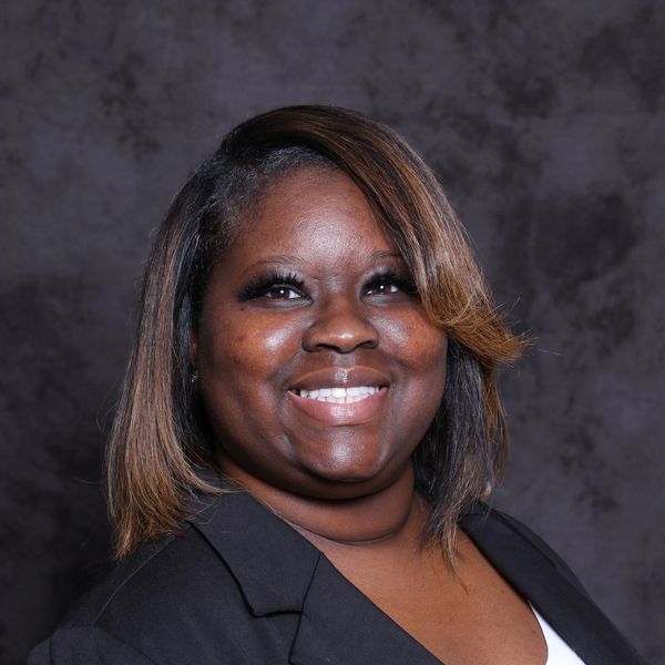 Professional woman smiling against a dark backdrop.