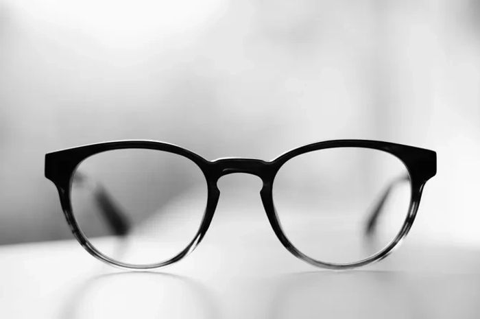 Black-framed eyeglasses in sharp focus on a blurred background.