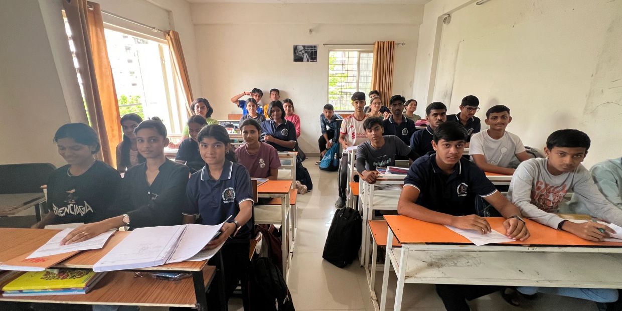 Students sitting in a classroom with notebooks and books.