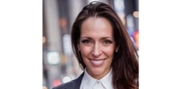 A smiling woman in a suit with a white blouse and gray jacket and long red hair