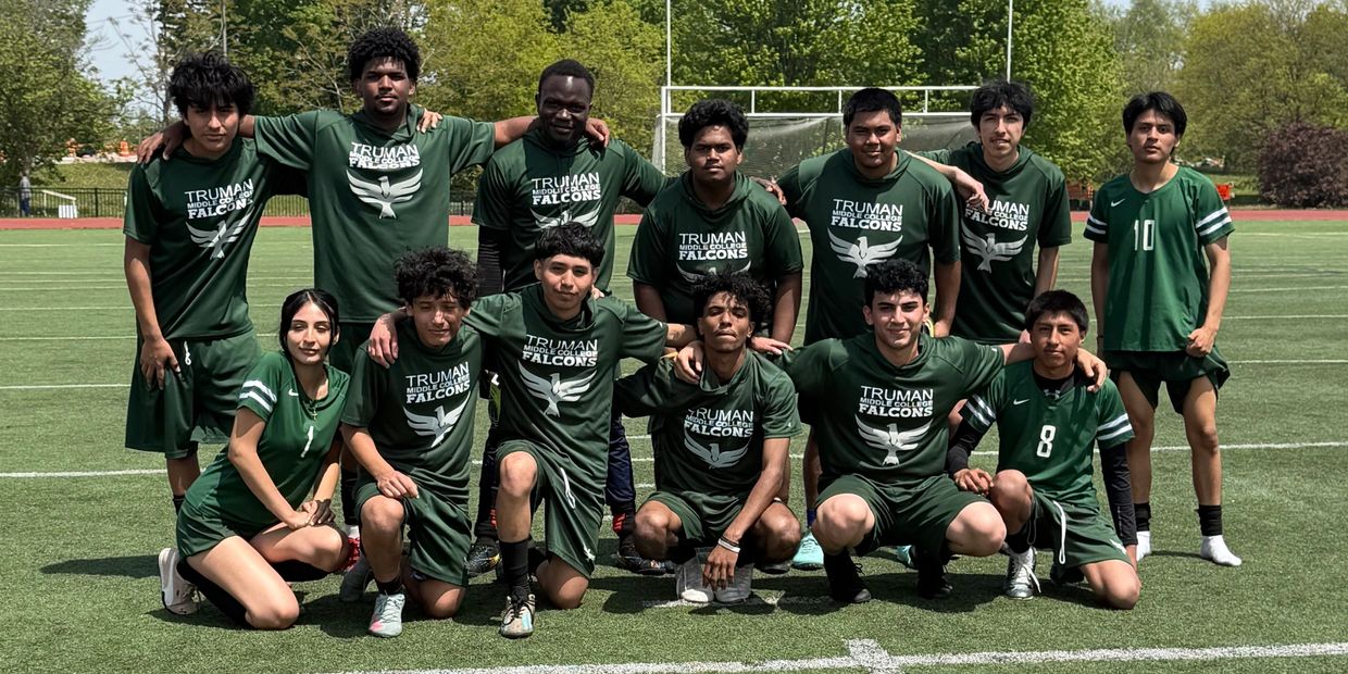A soccer team posing together on a field in green uniforms.