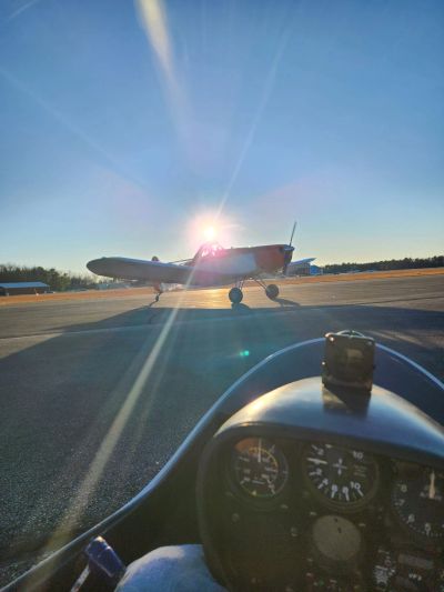 A small airplane on a runway with sunlight shining behind it.