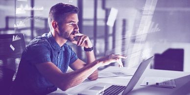 Man working late on a laptop in an office with digital data overlays.