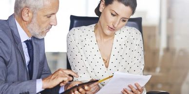 Two professionals reviewing documents in an office setting.