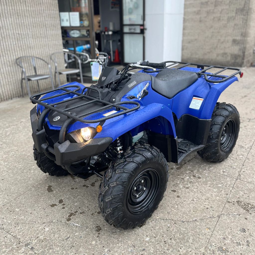 Blue Yamaha Kodiak ATV parked on a wet concrete surface.