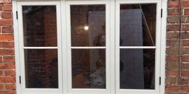 White-framed window on a red brick wall with visible pipes.