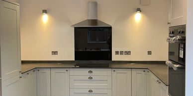 Modern kitchen with white cabinets and black countertop under warm wall lights.