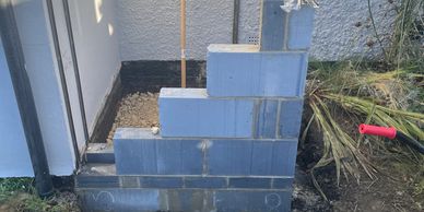 Partially constructed gray cinder block staircase outside a building.