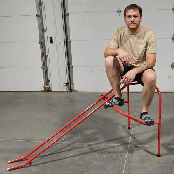 Man sitting on a small red slide indoors.