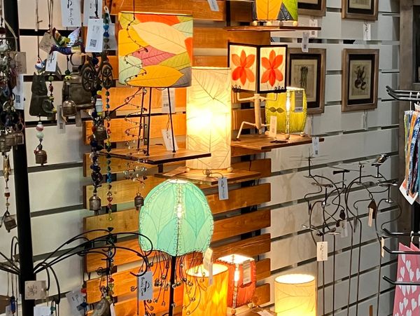 Colorful decorative lamps and wind chimes displayed on wooden shelves in a cozy shop.