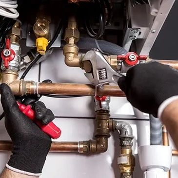 A man in black gloves repairing a pipe using a wrench