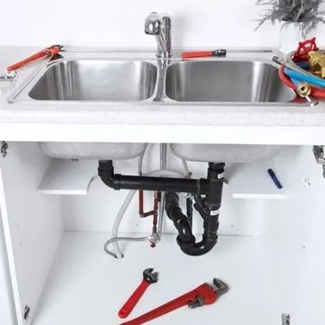 Double sink with exposed plumbing; tools and parts scattered