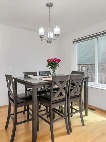 Modern dining area with dark wooden table, six chairs, and fresh flowers under a chandelier.