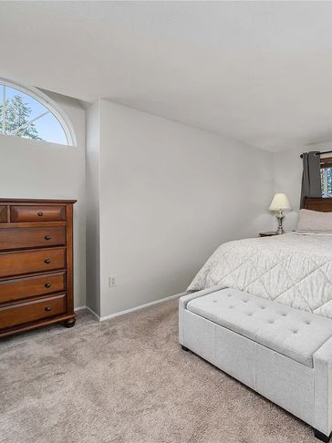Cozy bedroom with neutral tones and wooden dresser.
