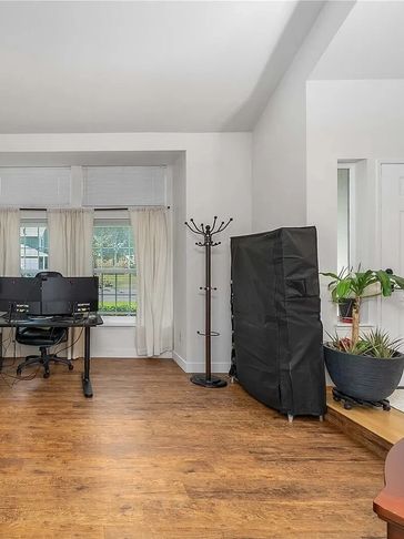 Modern home office with wooden flooring and large windows.