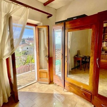 Sunlit room with wooden wardrobe, open door, and sheer curtains.