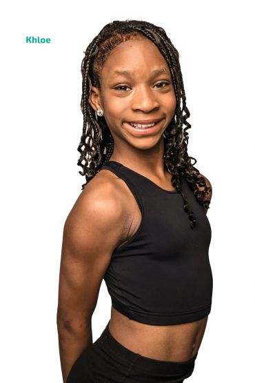 Smiling young girl with braided hair and earrings.
