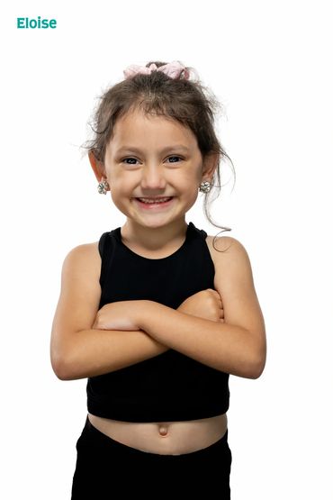 Smiling young girl with arms crossed in black outfit.