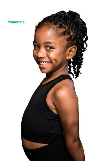 Smiling girl with braided hair in black outfit.