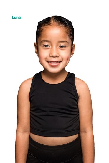 Smiling young girl in black outfit posing against white background.