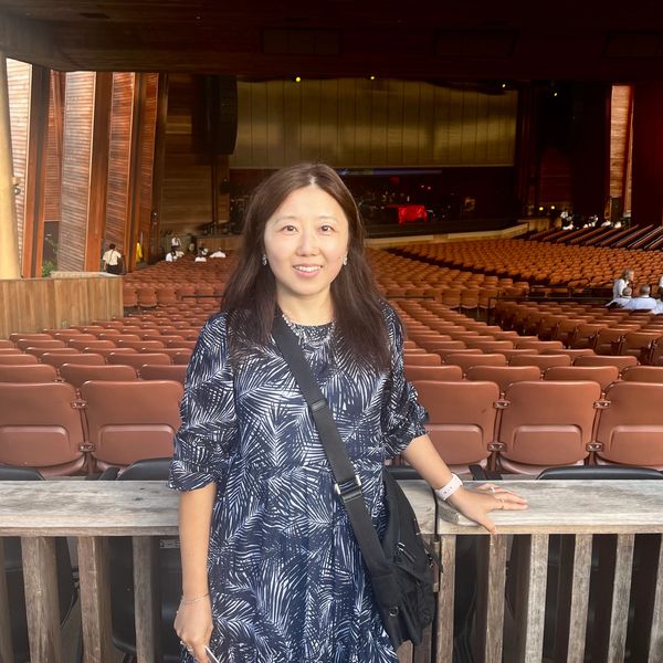 A woman posing inside an empty auditorium with wooden architecture.