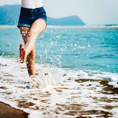 A girl in short jeans playing in the waves at the beach