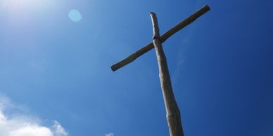 A wooden cross against a backdrop of clear, sunny skies