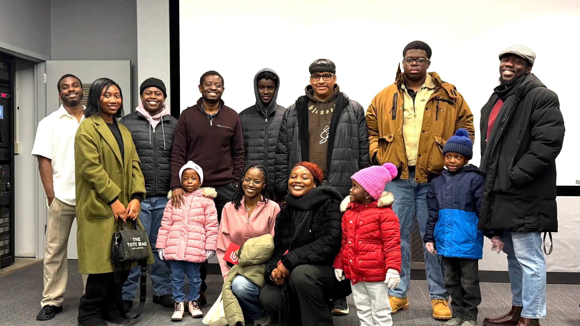 A diverse group of people posing indoors in winter clothing.