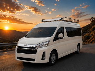 White van parked on a road during sunset with scenic hills in the background.