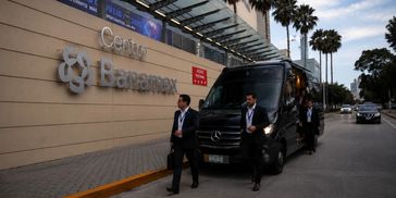 Security personnel escort a black van outside Centro Banamex.