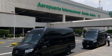 Two black vans parked outside Benito Juárez International Airport.